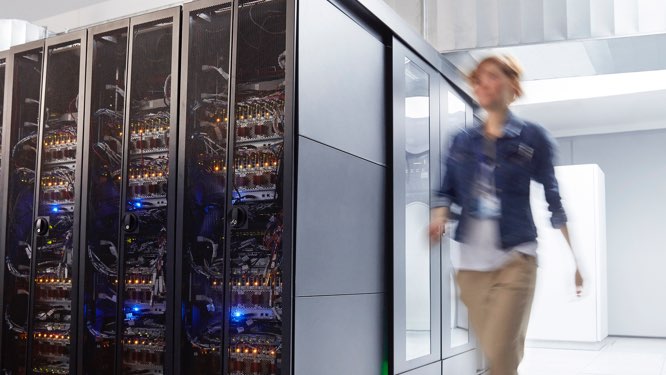 rows of server cabinets with a blurry woman along the right side